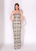A woman modeling a strapless, floor-length gown with an abstract black and off-white brushstroke pattern against a plain white studio background.