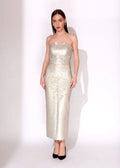 A woman modeling a strapless, floor-length champagne-colored sequined gown with black pointed-toe heels, standing against a plain white studio background.